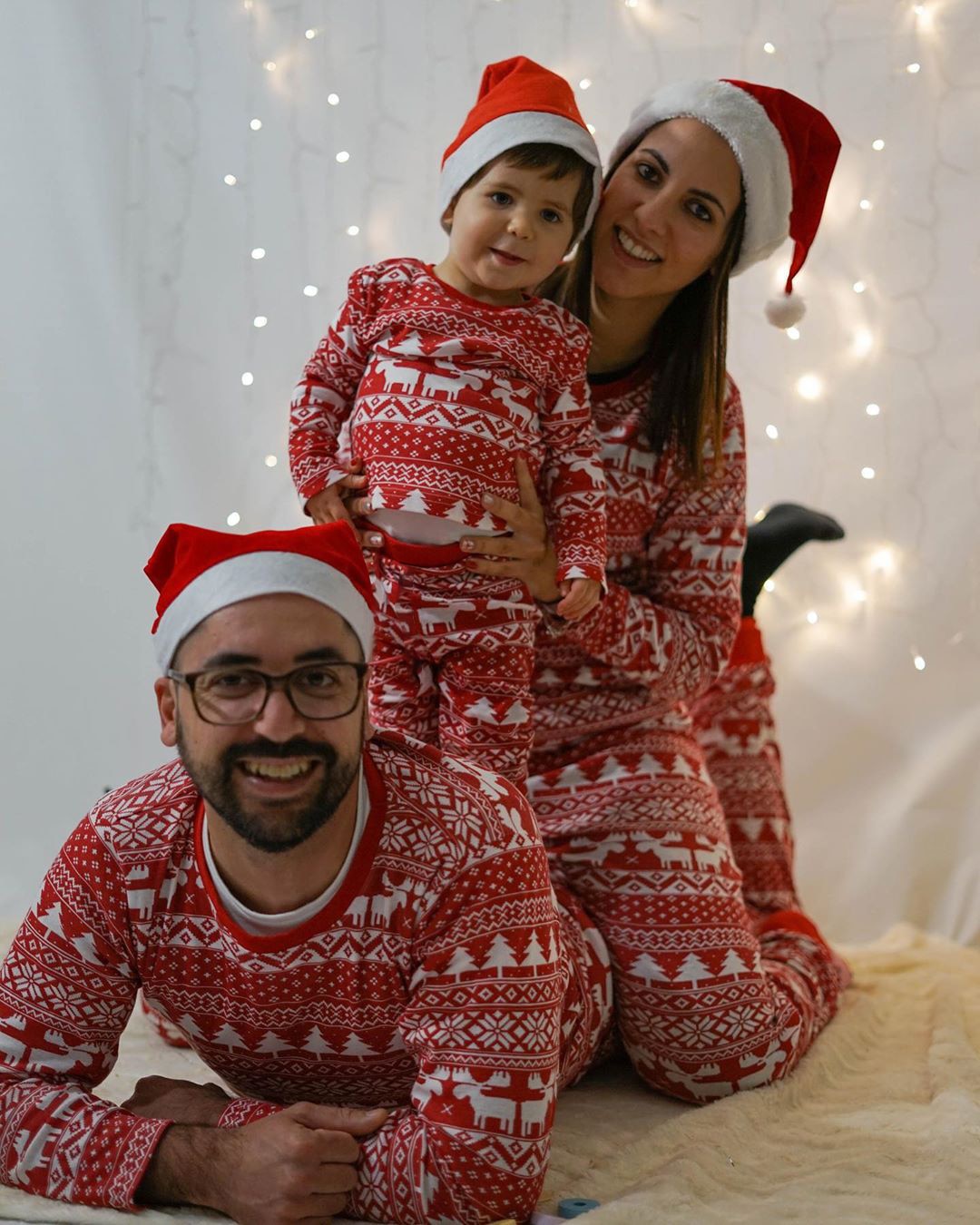 famille d'une maman un papa et un enfant en pyjama de noel assortis sur fond blanc lumineux