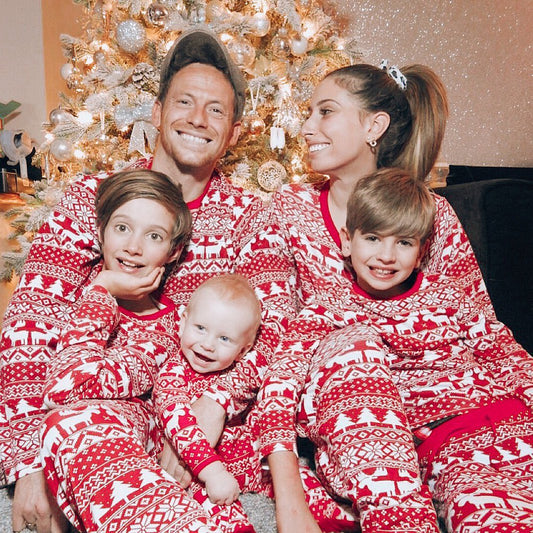 famille en pyjama de noel assortis devant leur sapin de noel