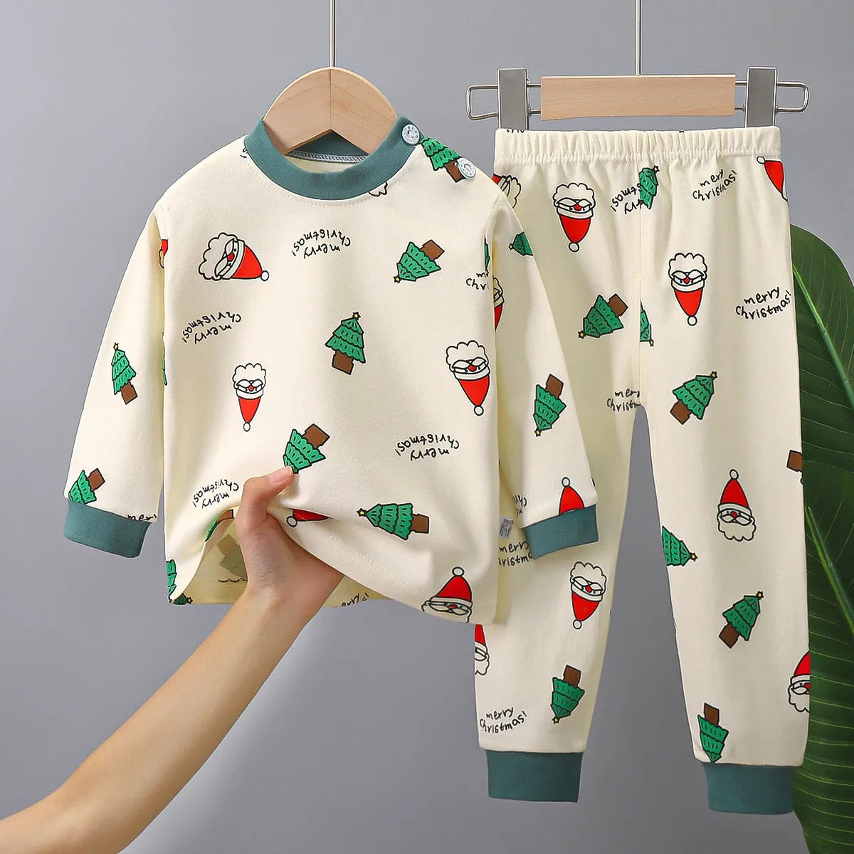 photo d'un Pyjama Bébé,Enfant Noël, comlposé d'un haut à manche longue et un pantalon tous les deux beige avec des motifs de têtes de père noël et de sapin 