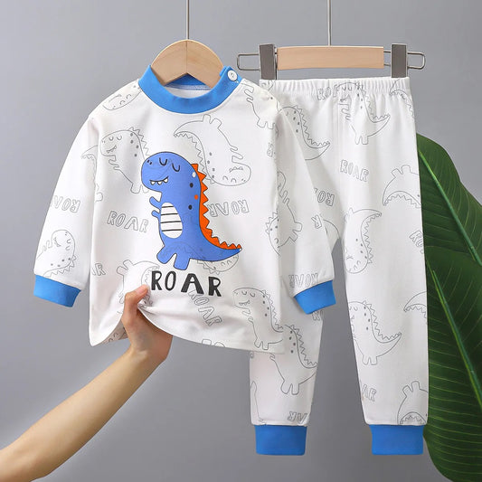 Pyjama pour enfant à manches longues avec motif préhistorique, haut blanc avec liseré bleu et pantalon assorti.