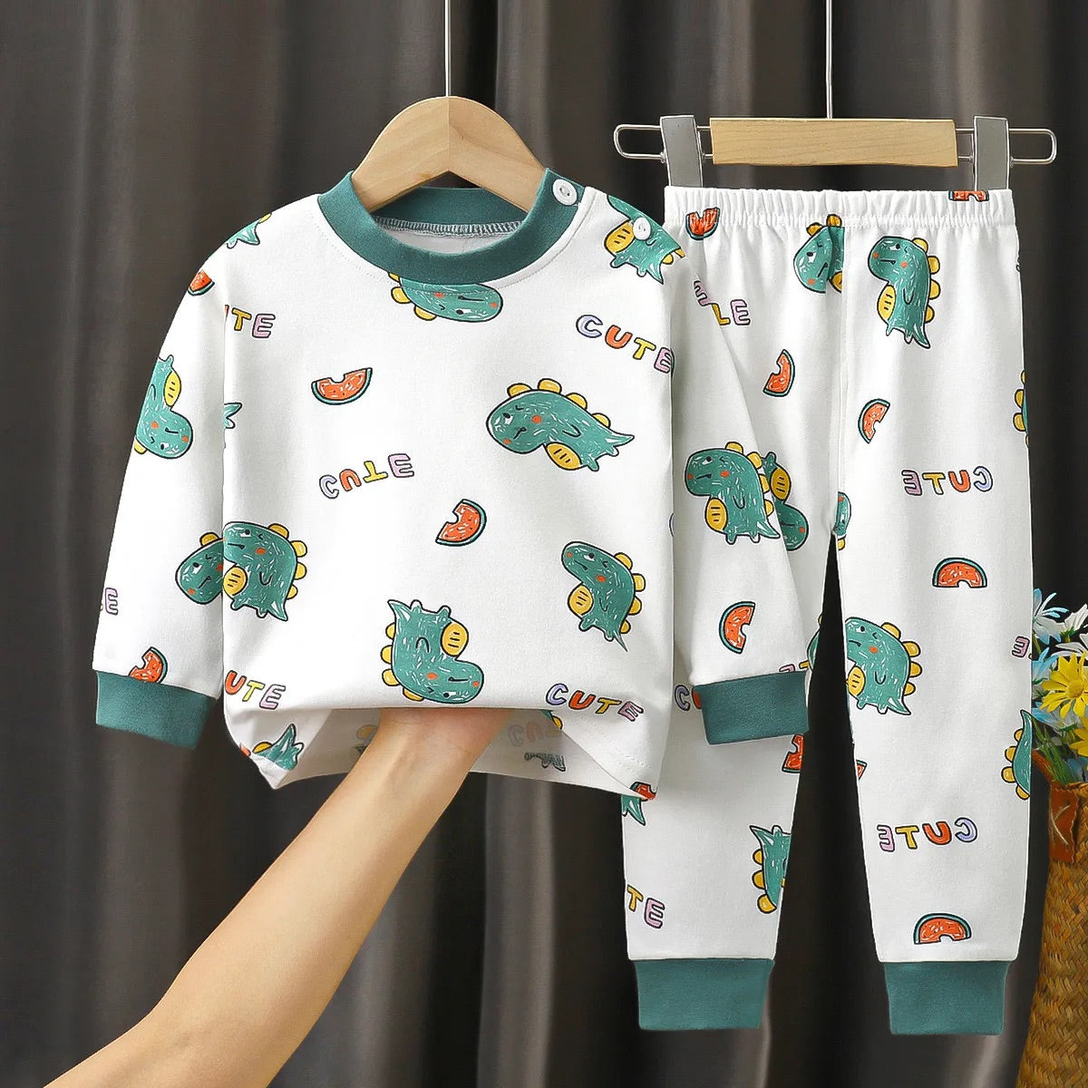 Ensemble de nuit pour enfant blanc avec motifs colorés de dinosaures et éléments fruitiers, accompagné de bordures vertes.